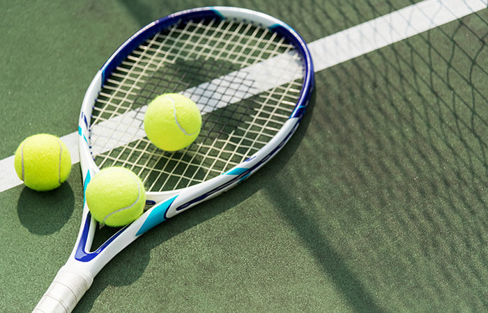 Racket and tennis balls on a tennis court in Maine